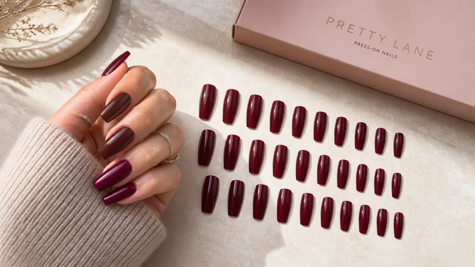 Coffin press-on nails in a deep berry shade with 24 tips laid out in size order