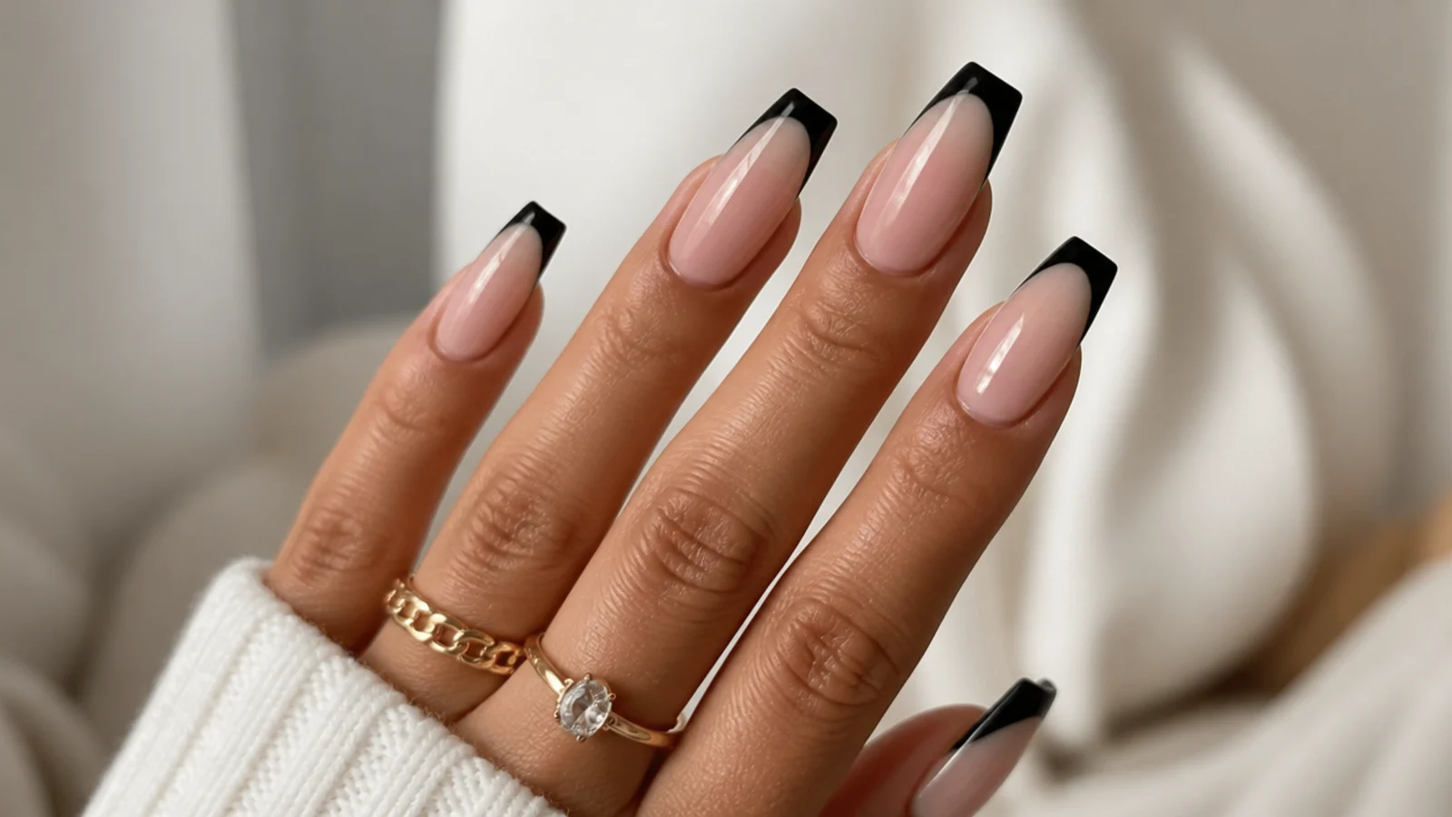 Coffin nails with sharp black French tips over a nude base at medium length