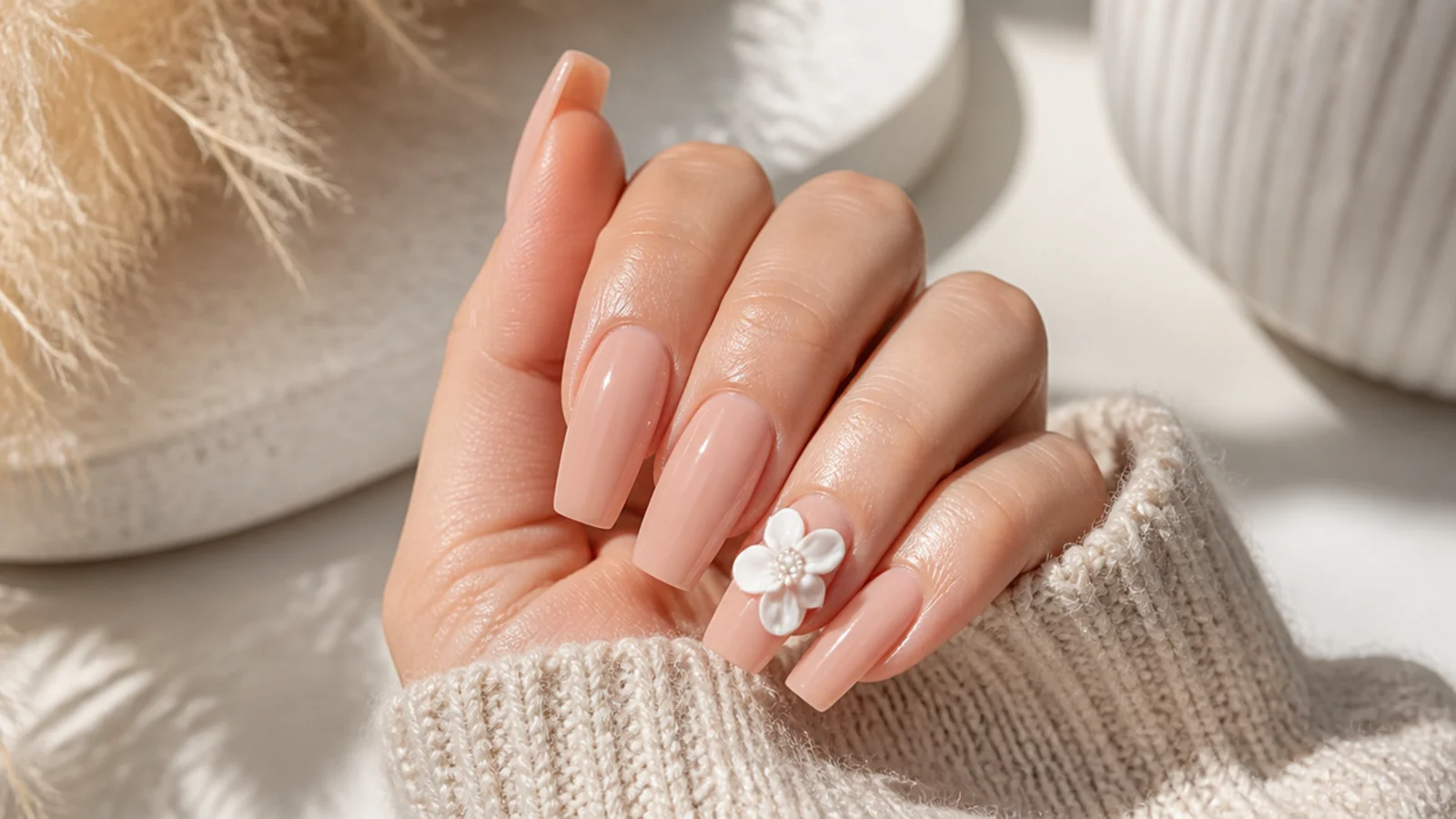 Nude coffin nails with a single raised white 3D flower on the ring finger
