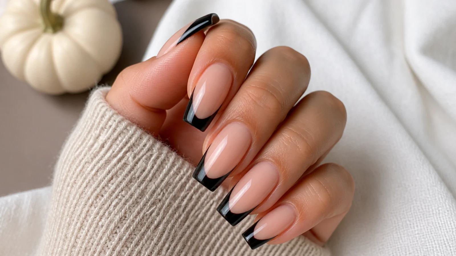 Coffin nails with a sharp black French tip on a sheer nude base for Halloween season