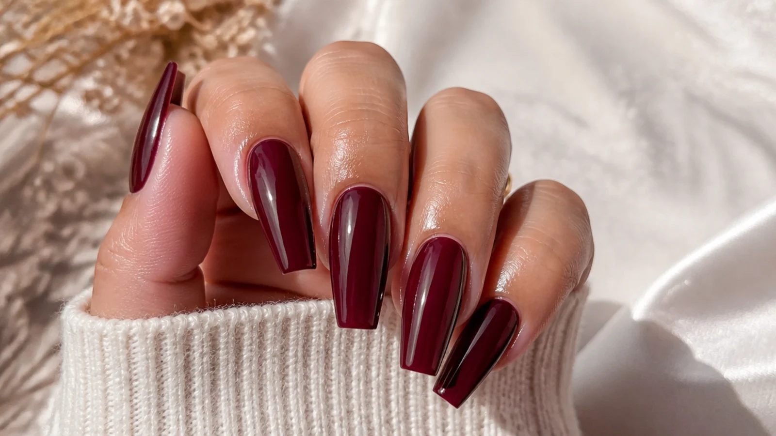 A finished burgundy coffin manicure with cuticle oil applied for longevity