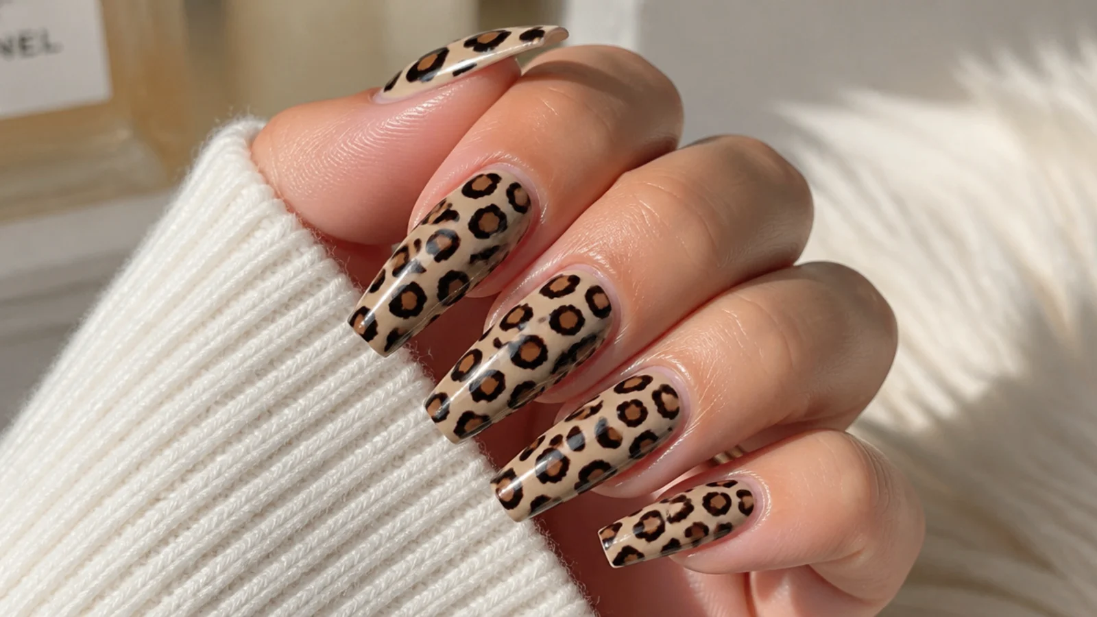 Long coffin nails with brown and black leopard spots on a soft beige base