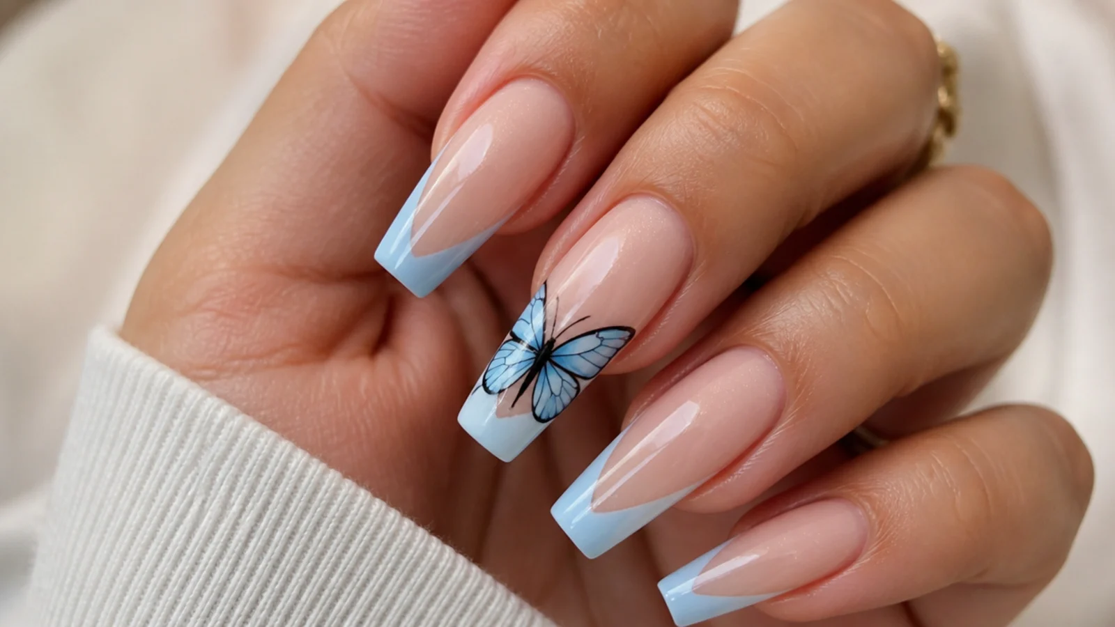 Long coffin nails with a hand-painted blue butterfly spanning an accent nail