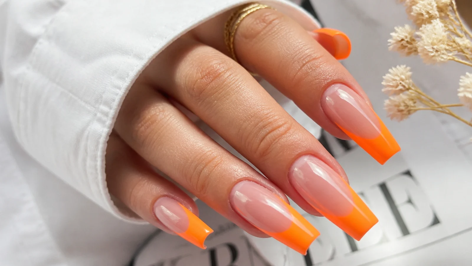 Long coffin nails with bright neon orange tips on a clear extension