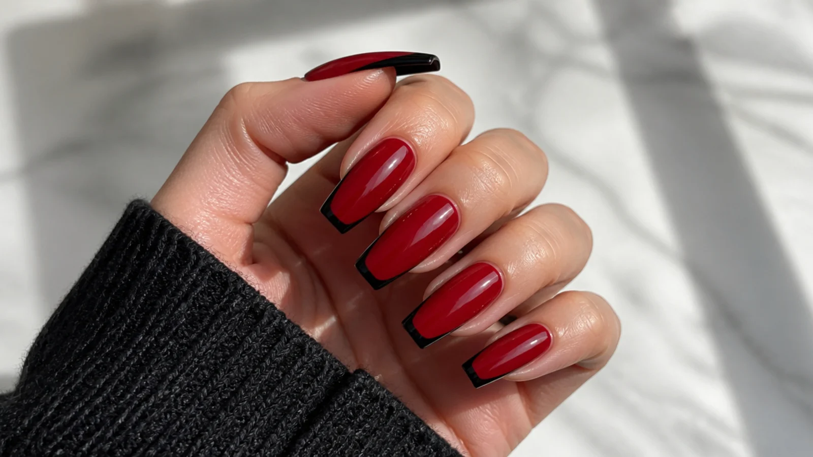 Red coffin nails with sharp black French tips following the flat tip line