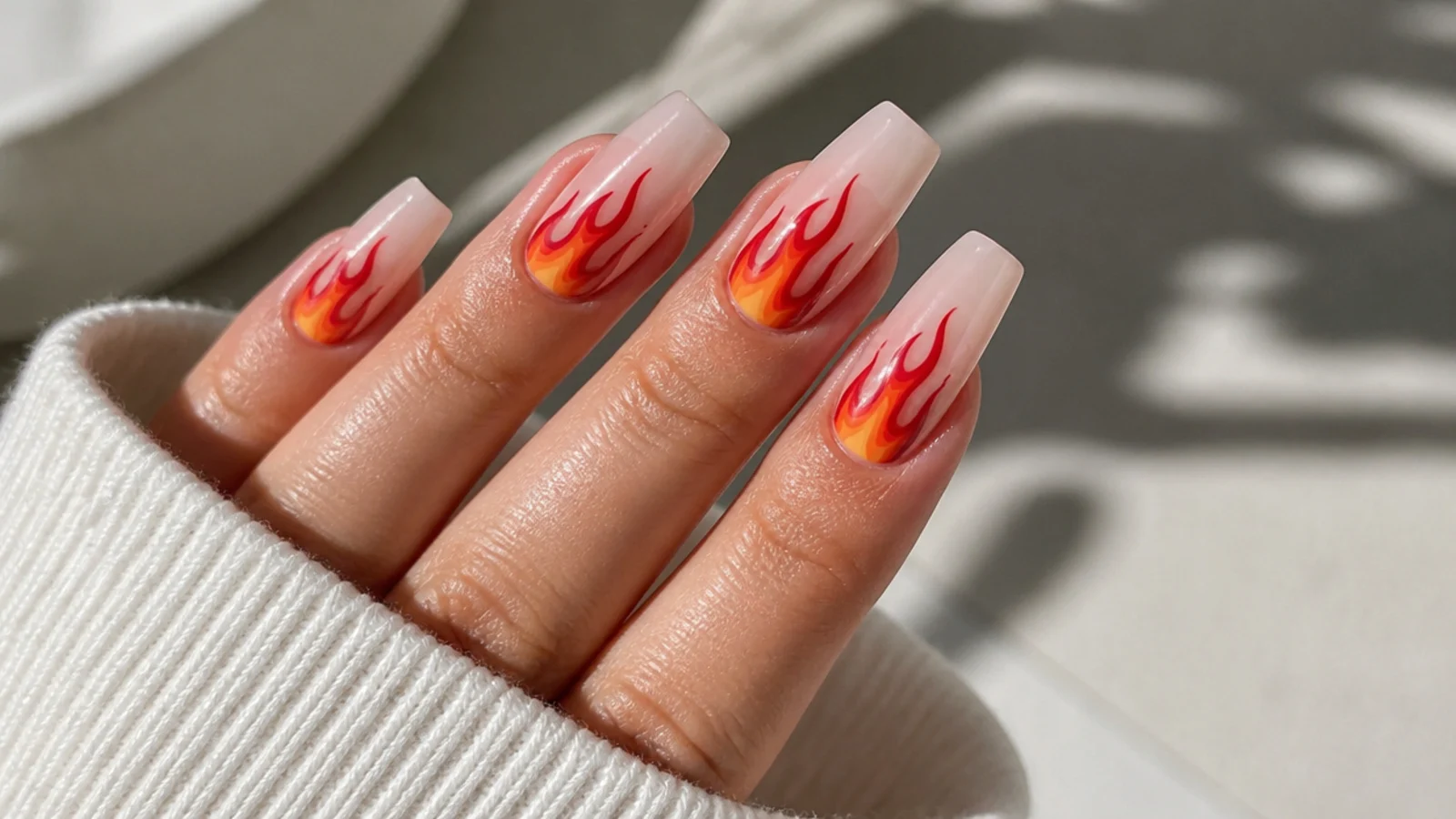 Sheer coffin nails with red and orange flame nail art rising from the cuticle