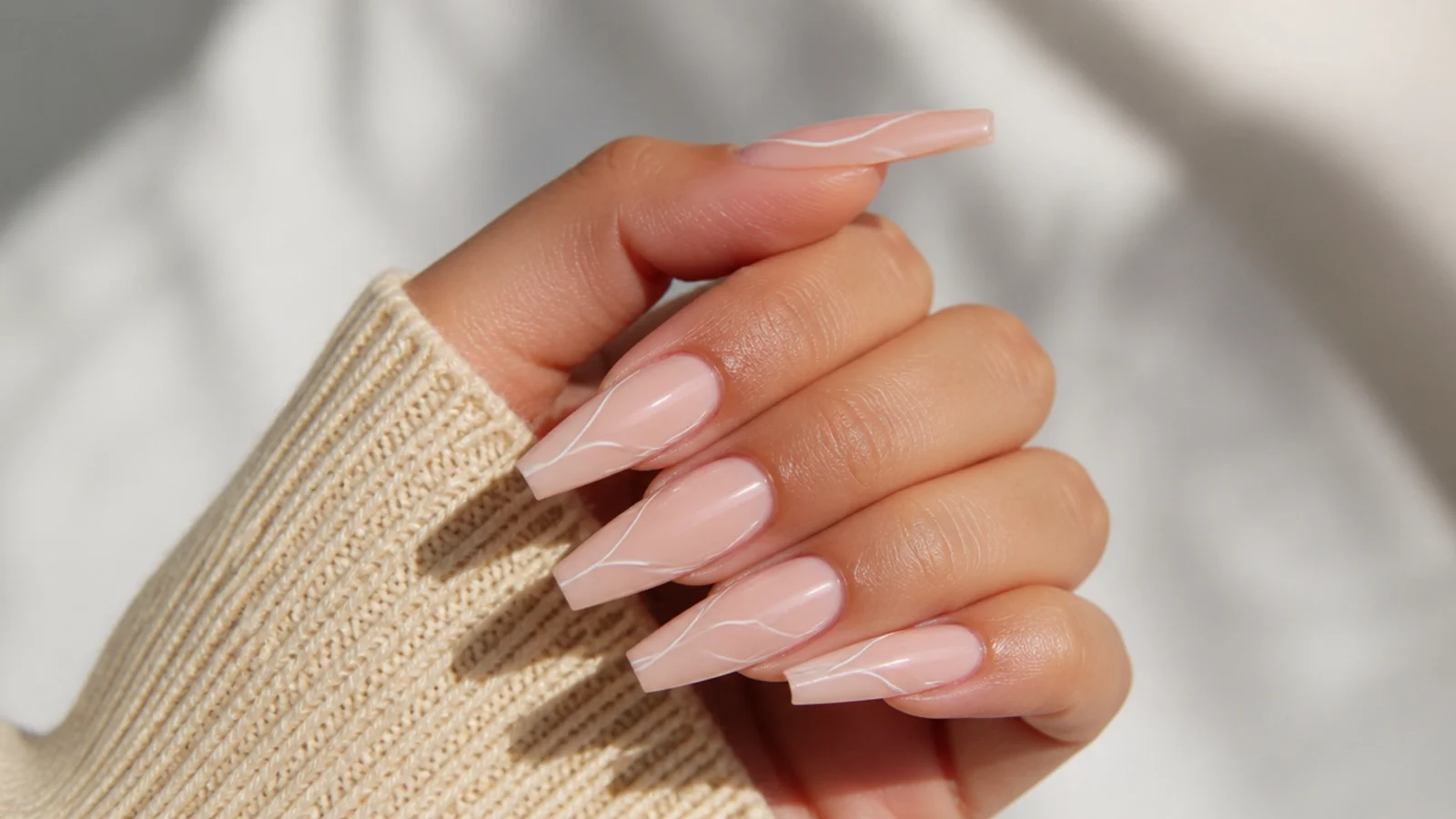 Long coffin acrylic nails with thin white swirl lines curving across a nude base