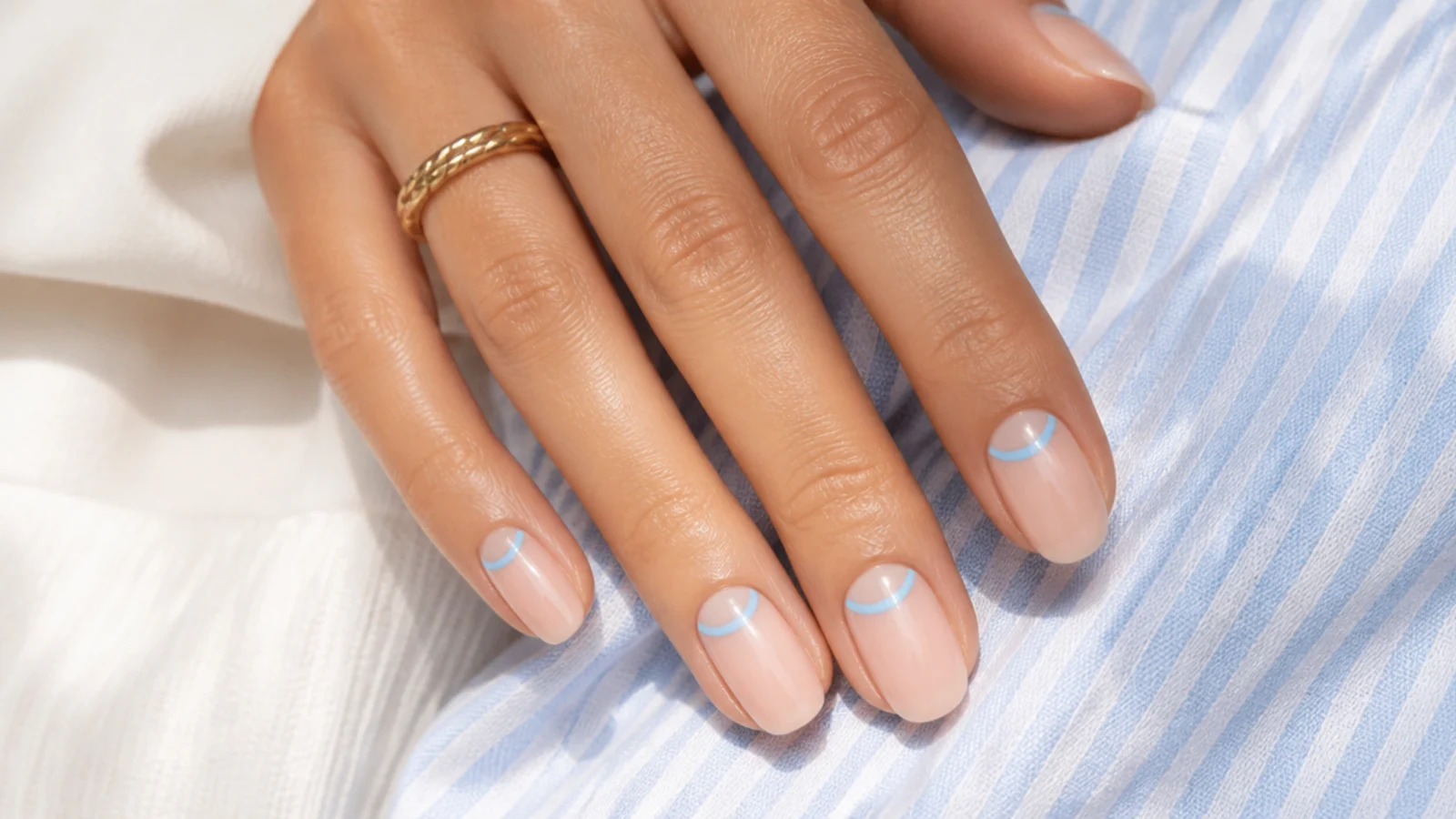 Sheer nails with a lagoon blue flipped French band of color at the cuticle
