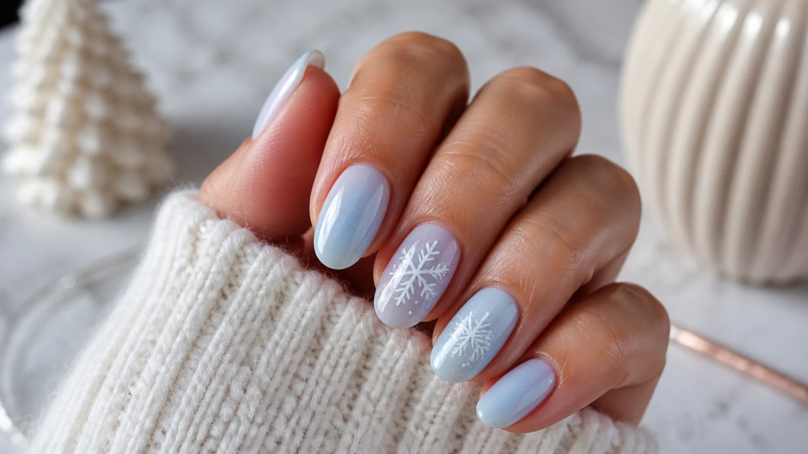 Sheer icy blue nails with fine white snowflakes painted on two accent nails