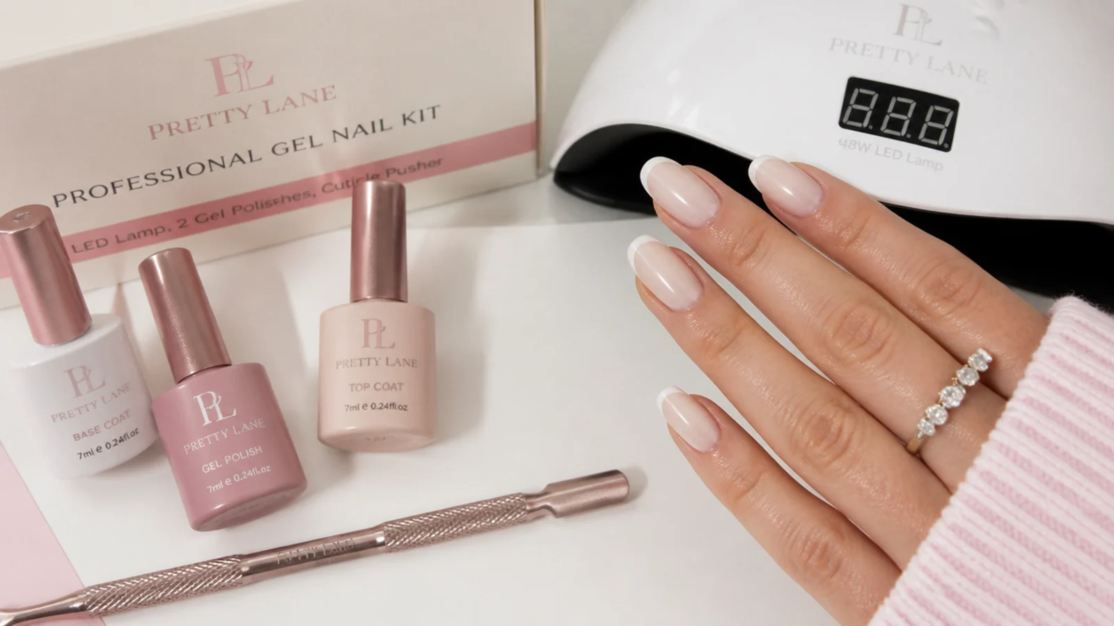 Gel nail kit with a 48 watt LED lamp, milky nude and pink gel bottles and a cuticle pusher on a white table