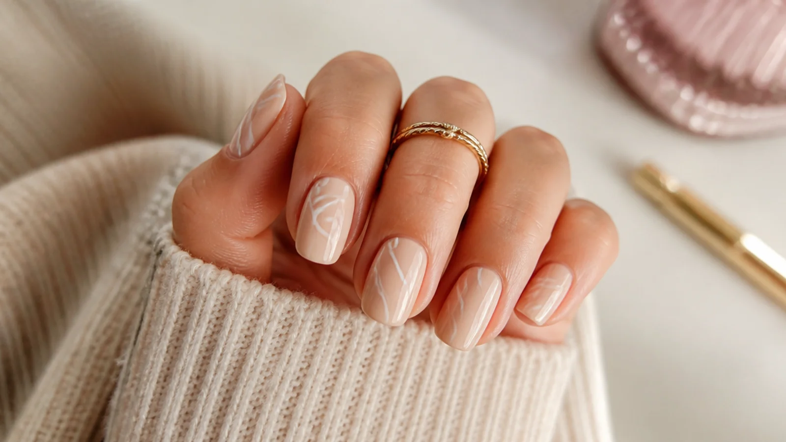 Nails with wobbly hand-painted white abstract swirl lines over a beige base