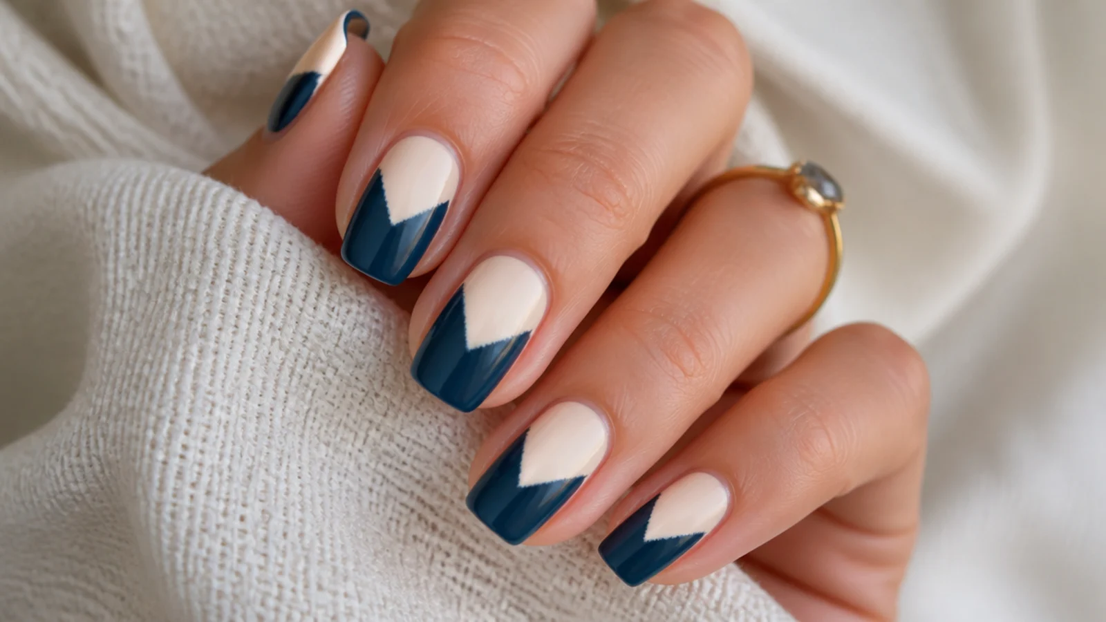 Nails with a two-tone chevron split in cream and navy showing a slightly bleeding edge