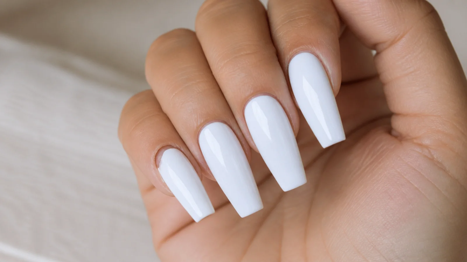 Long coffin press-on nails in glossy white showing one lifted nail at the sidewall