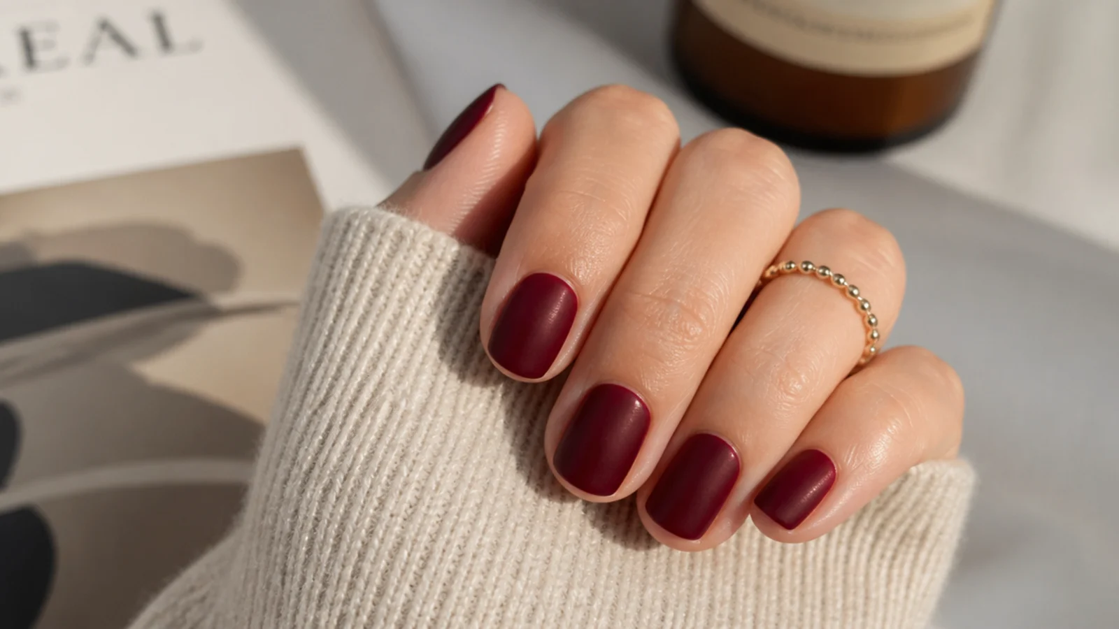 Short nails in oxblood red under a flat matte top coat with a velvet suede texture