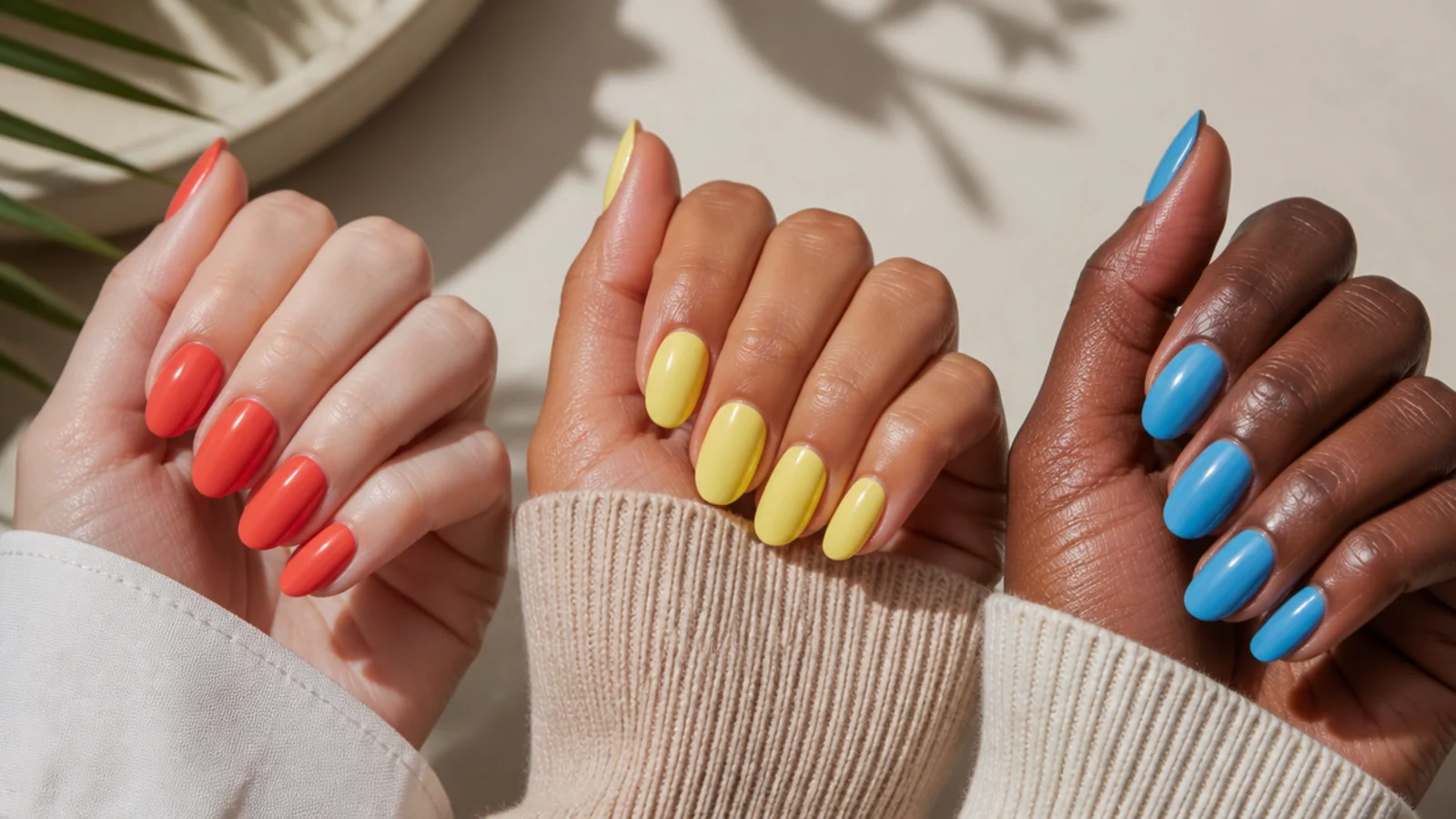Three hands in fair, olive and deep skin tones each wearing a different bright summer nail color