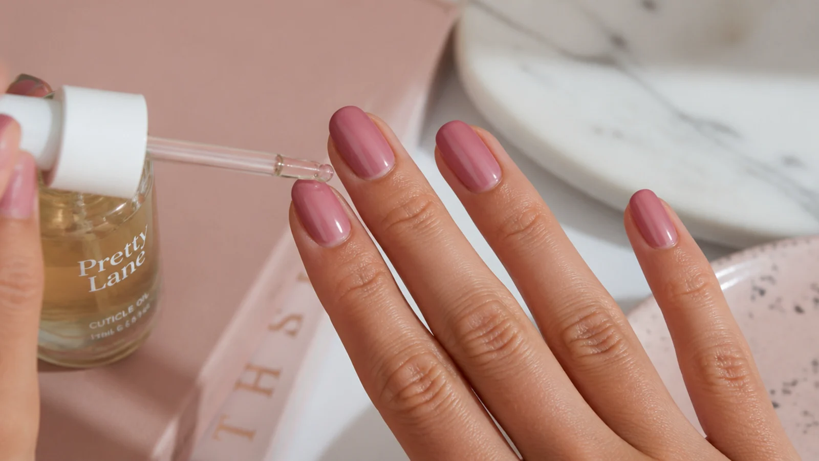 Cuticle oil being applied to a week-old at-home manicure that still looks glossy