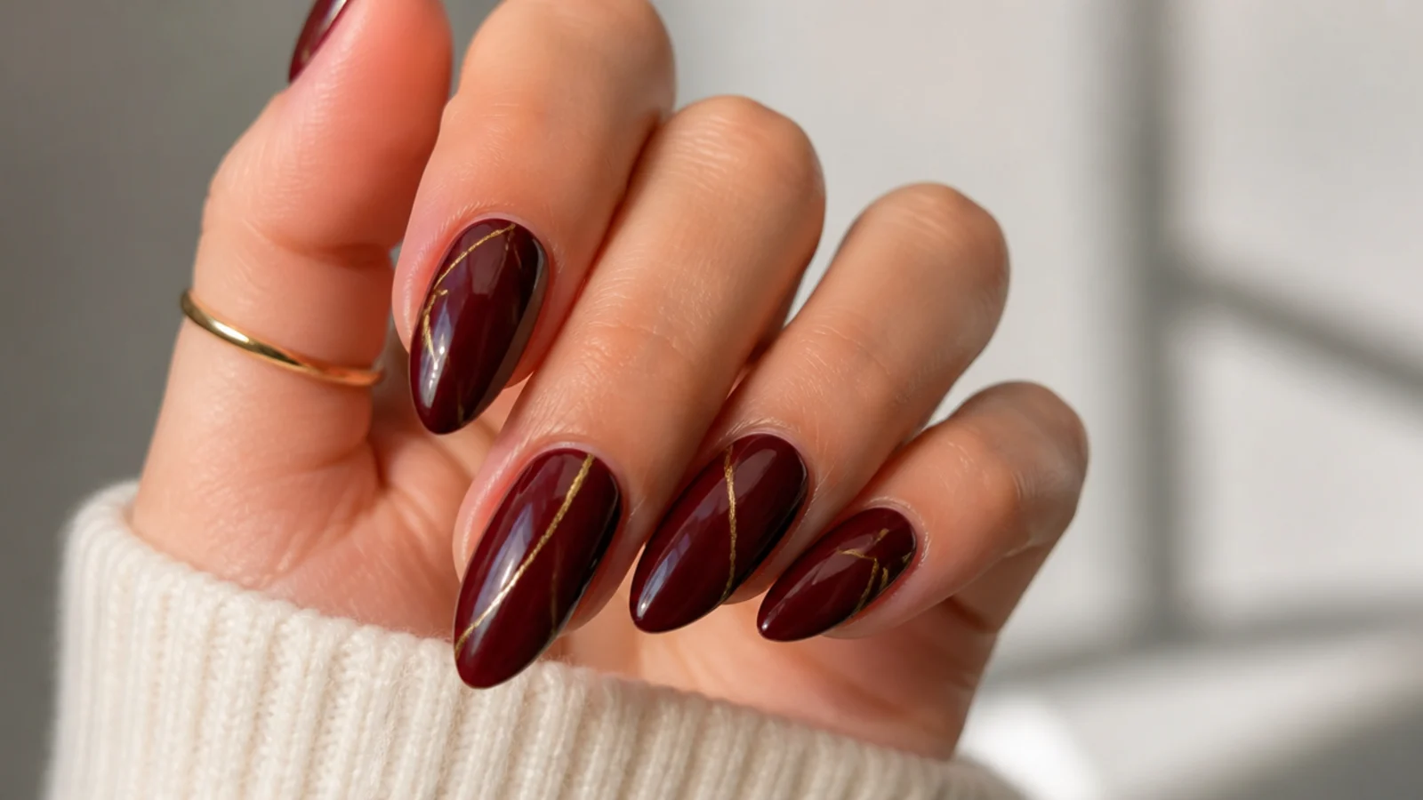 Oxblood almond acrylic nails with a thin gold foil line accent