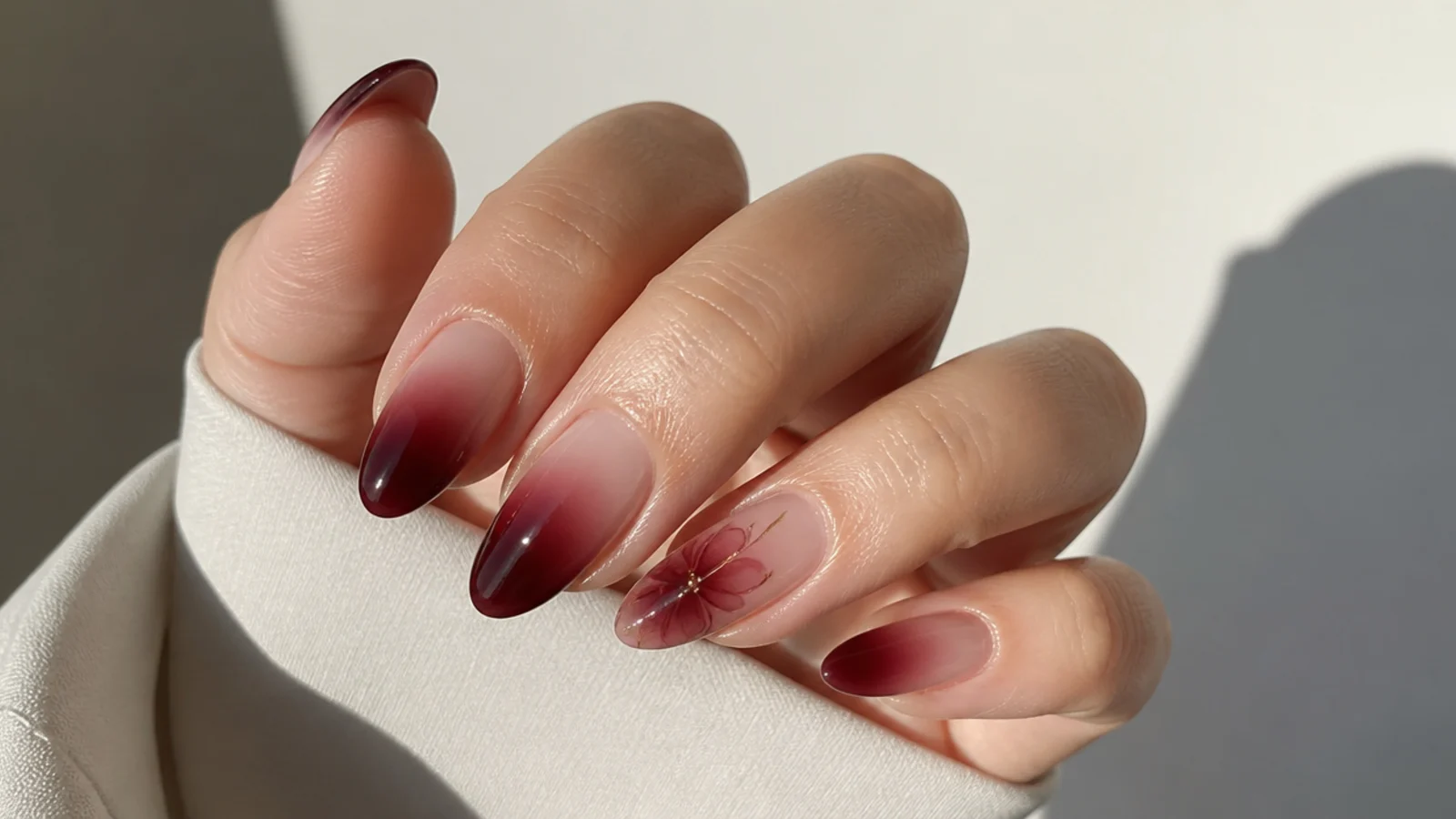 Sheer wine red over a milky base on almond acrylic nails