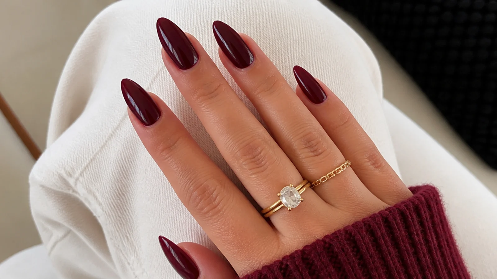 Deep oxblood almond acrylic nails with a glossy finish on warm-toned hands