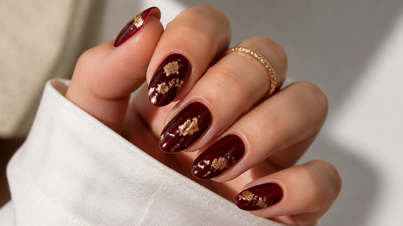 Oxblood dark feminine nails with scattered gold foil flakes