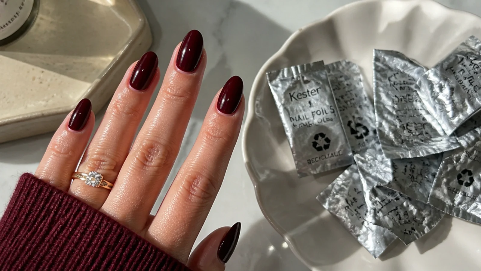 A well-sealed deep oxblood manicure beside acetone foils for safe removal