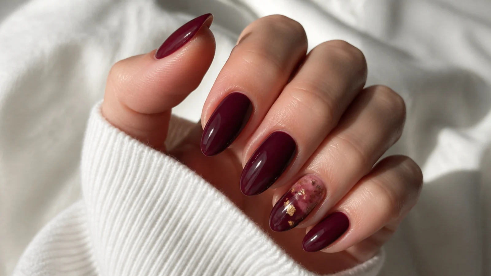 Deep warm-toned berry and oxblood dark feminine nails on a relaxed hand