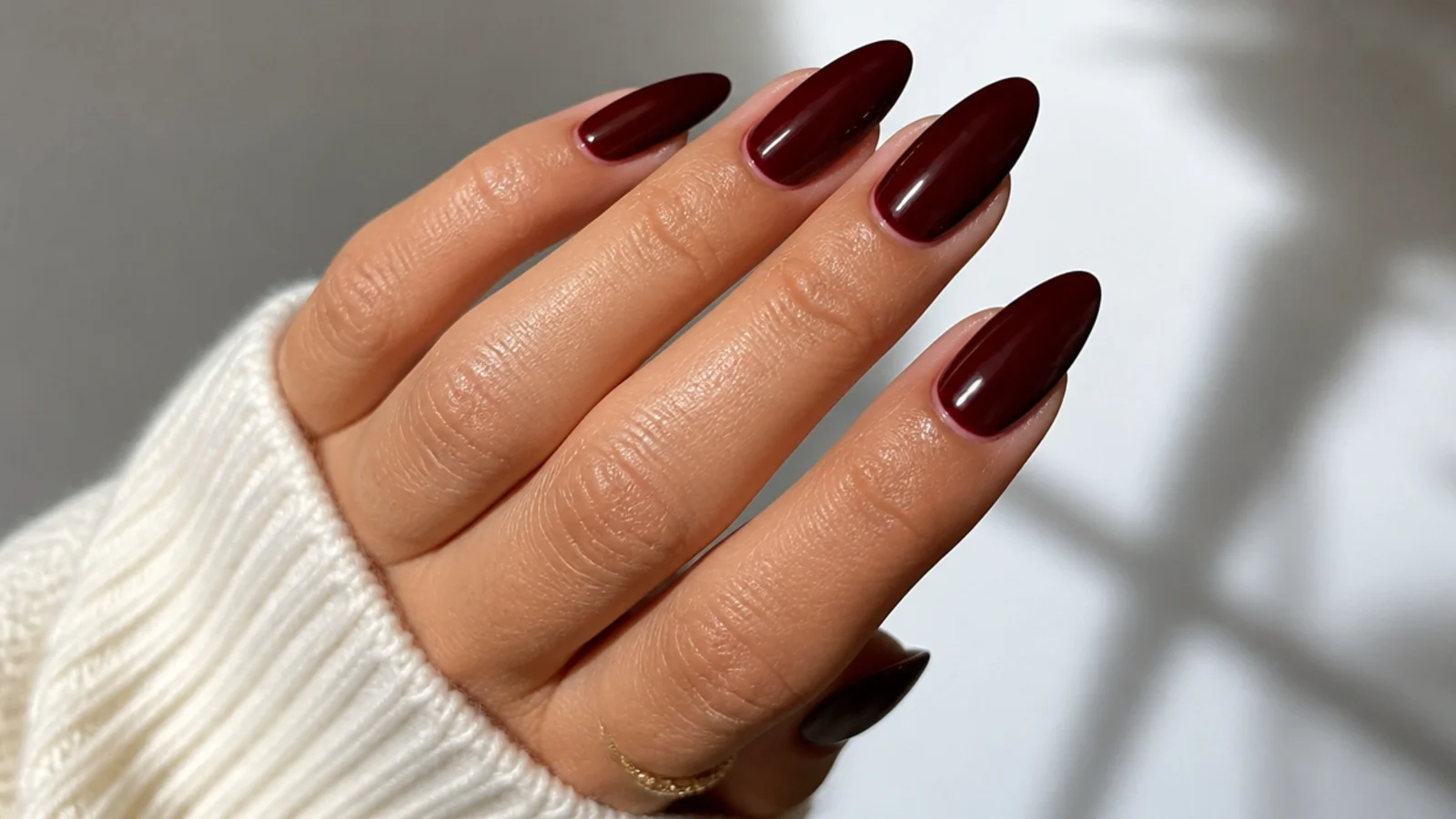 High-gloss wine red almond nails on warm-toned hands