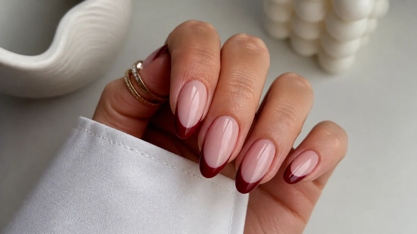 Sheer nude almond nails with a deep berry French tip