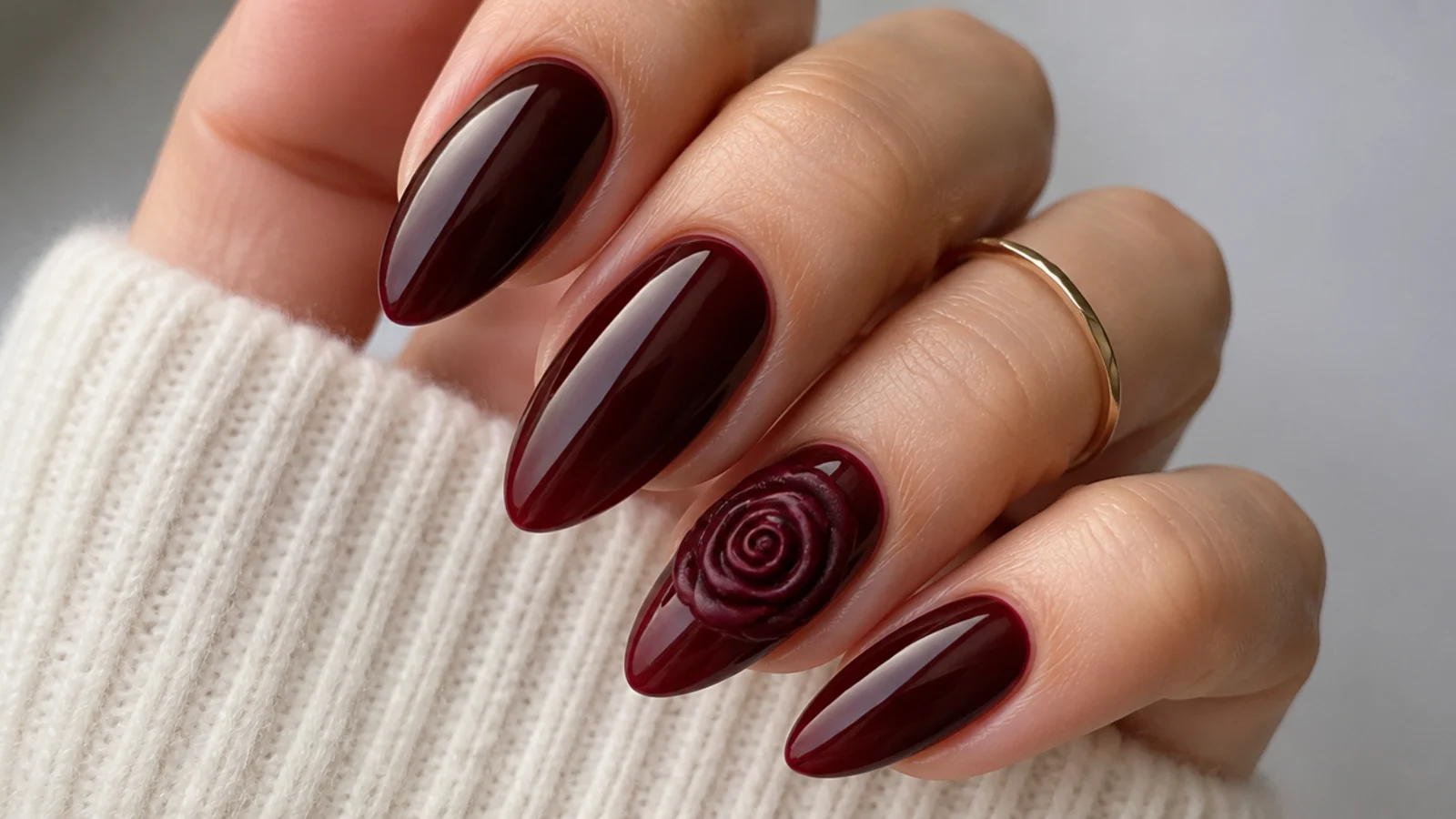 Oxblood almond nails with a sculpted 3D gel rose on one accent nail