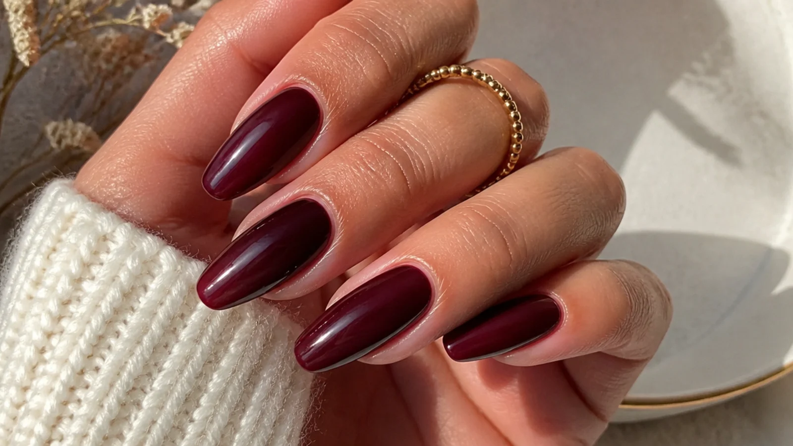 Sheer cherry cola red-brown almond nails on warm hands