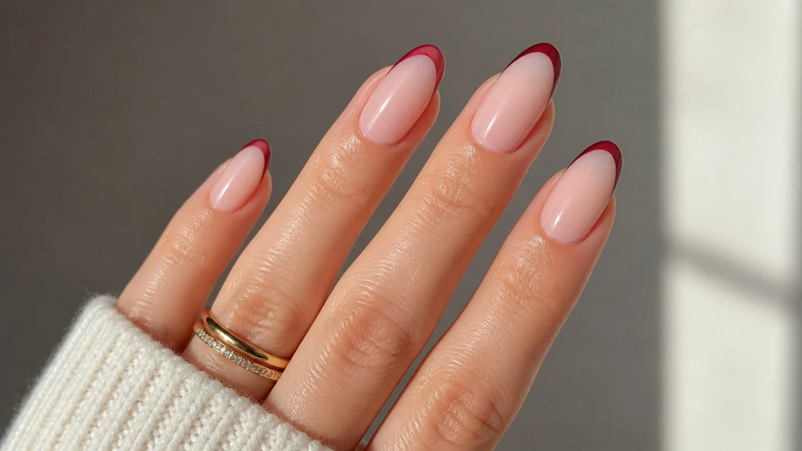Sheer nude almond nails with a thin deep red micro-French tip
