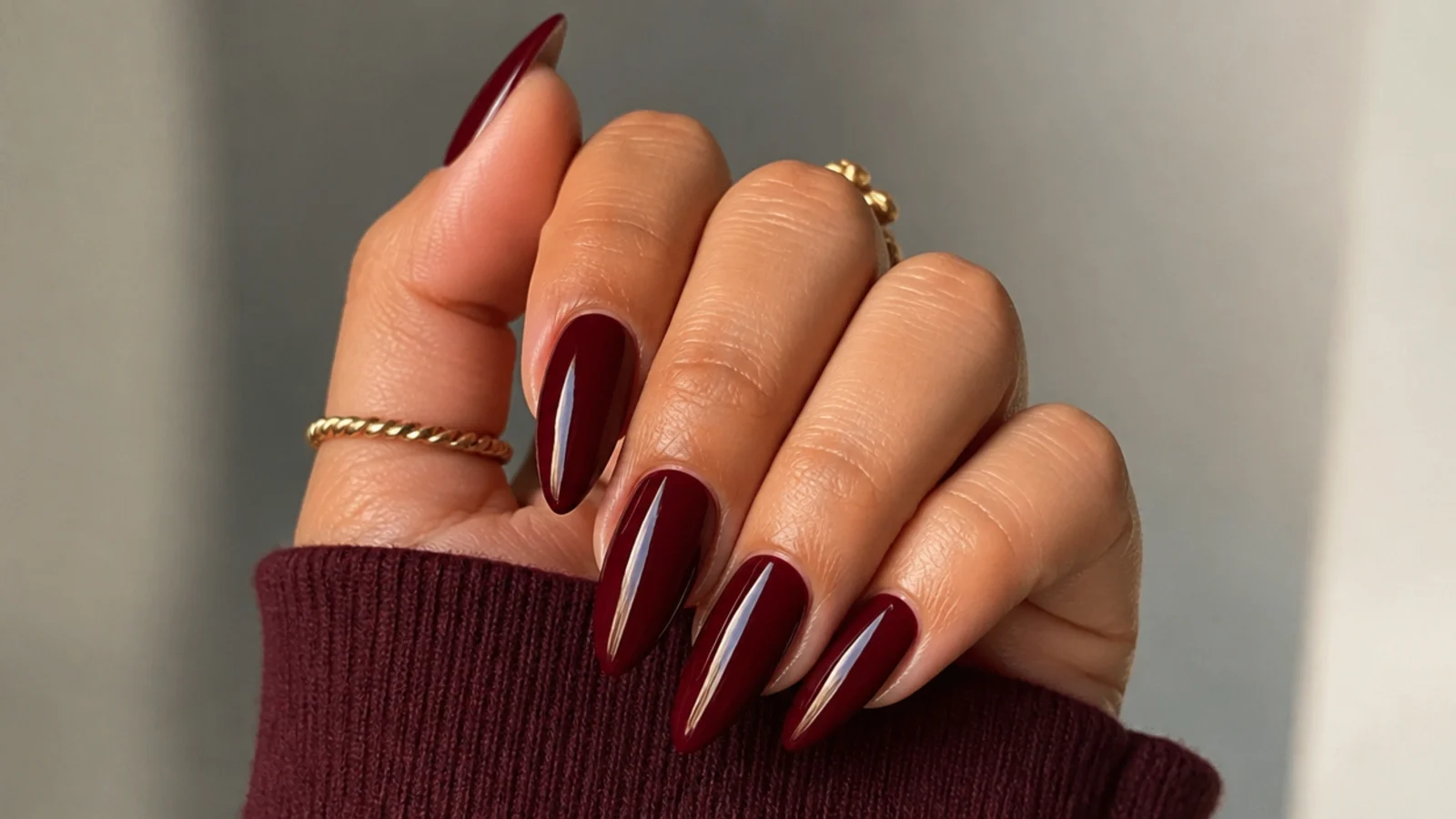 Glossy oxblood dark feminine almond nails on warm-toned hands