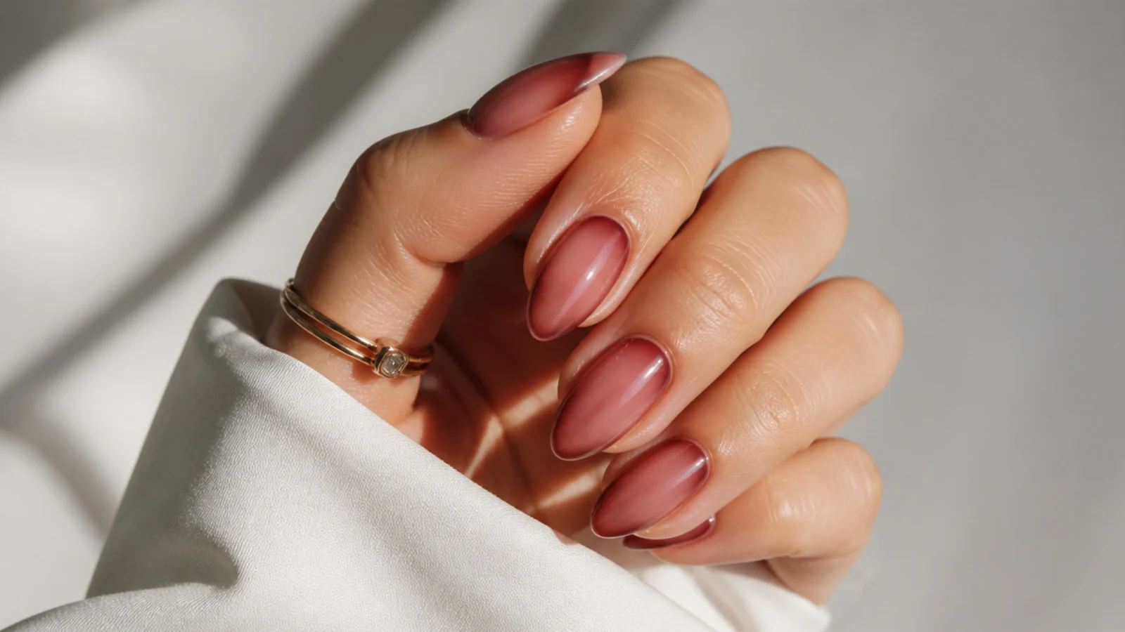 Sheer berry-tinted almond nails with the natural nail showing through
