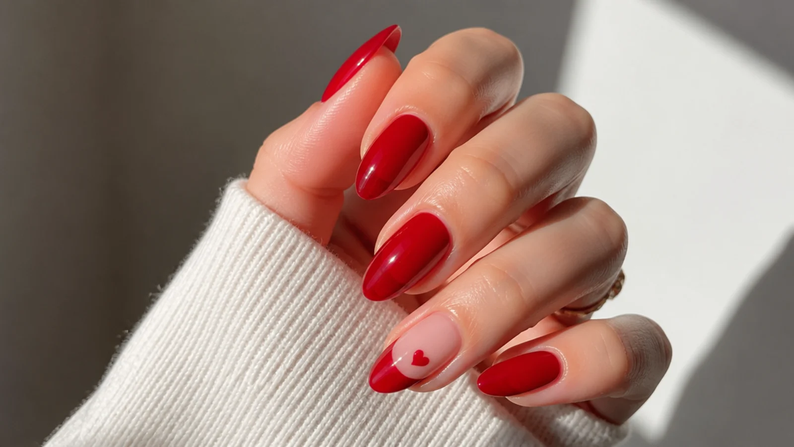 Sheer red nails with a tiny negative-space heart on one accent nail