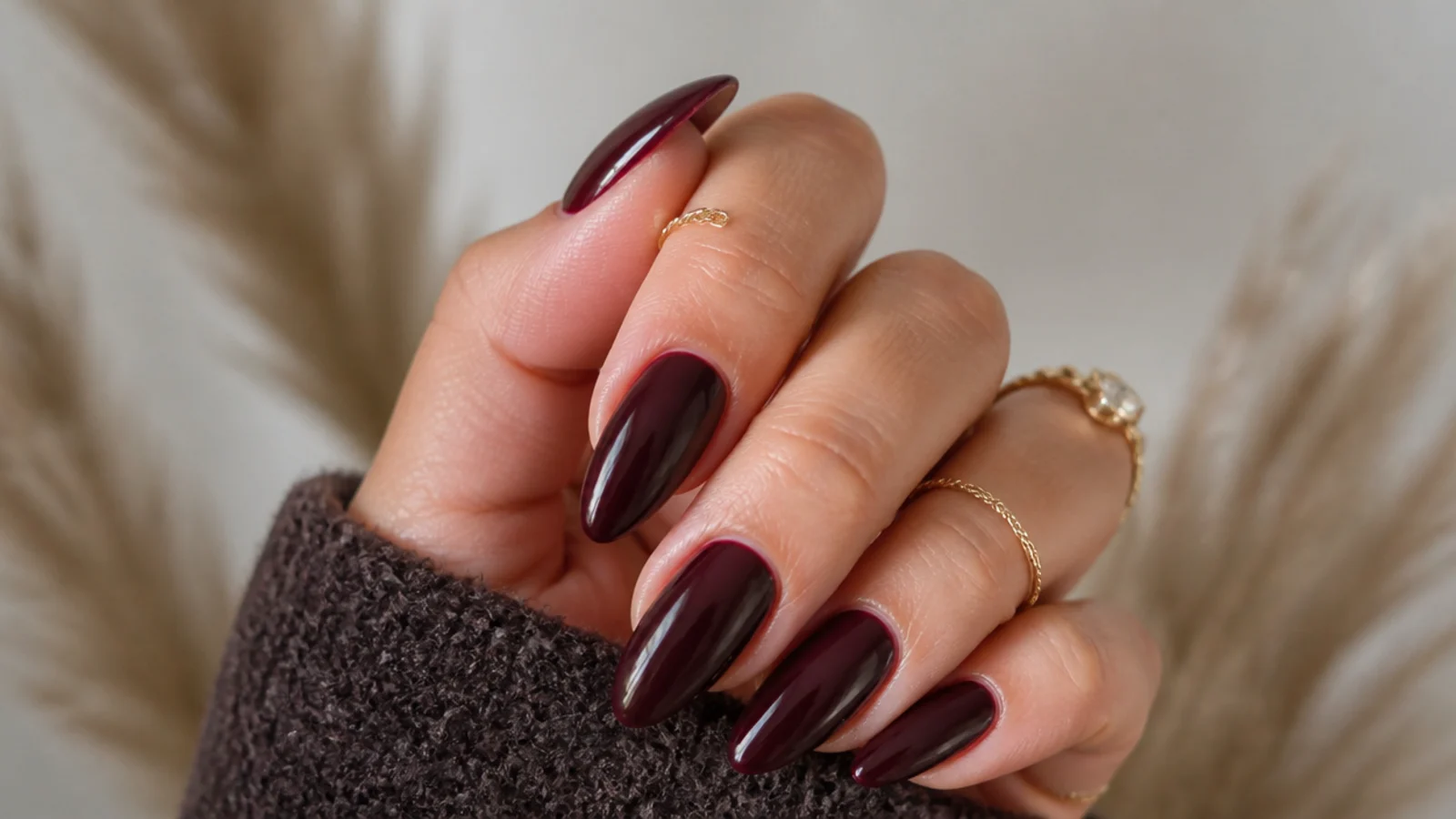 Glossy oxblood almond dark feminine energy nails on a warm-toned hand