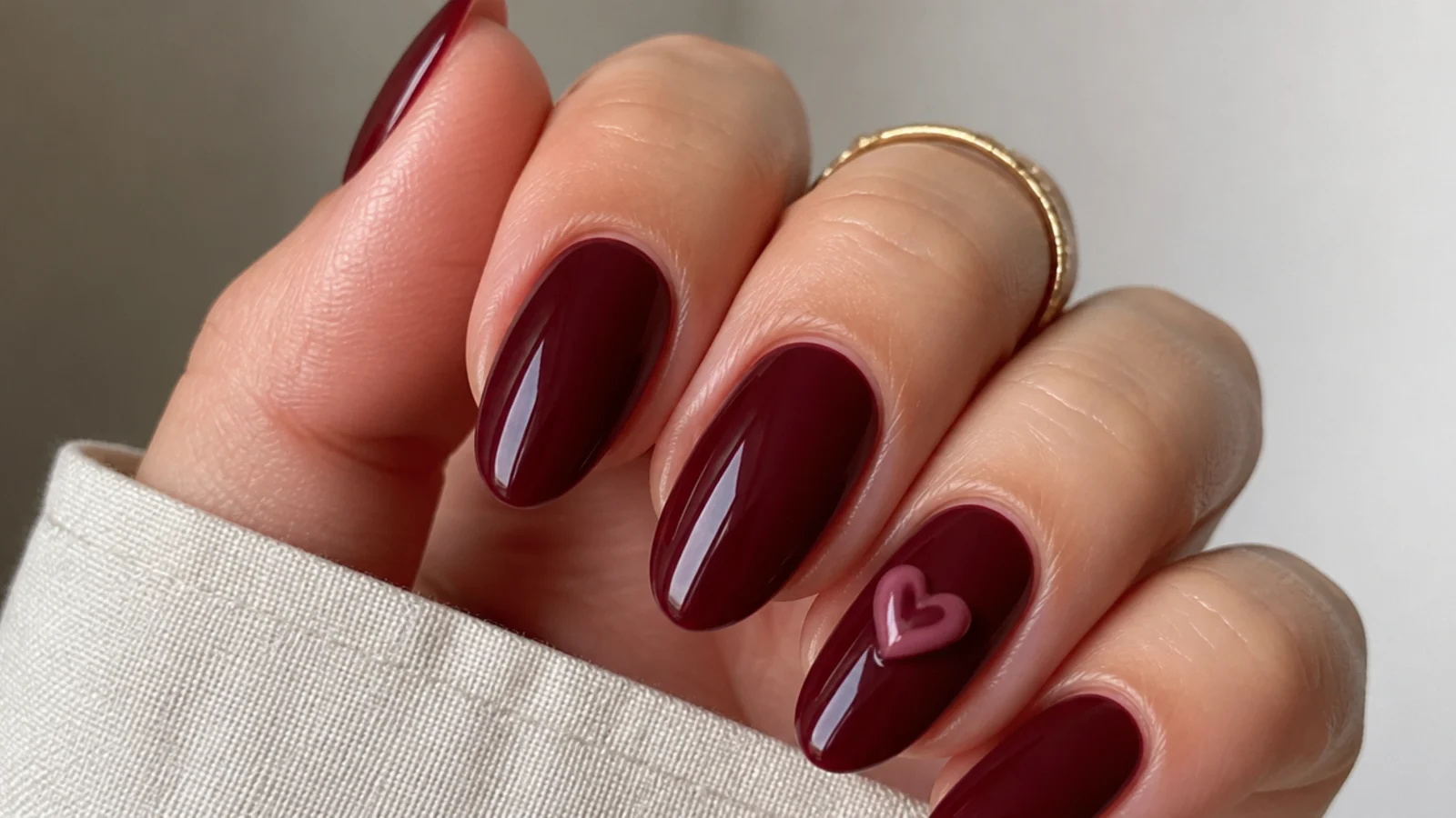 Deep berry almond nails with a small raised 3D heart on the accent nail