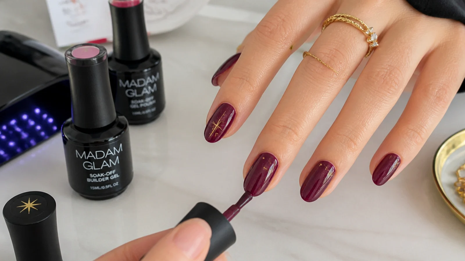 At-home dark feminine gel supplies with a deep berry nail mid-application