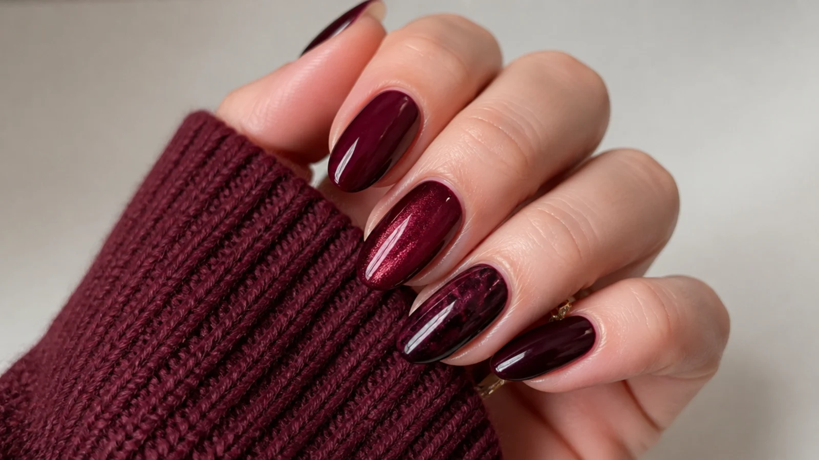 Glossy dark feminine almond nails in deep oxblood and berry tones