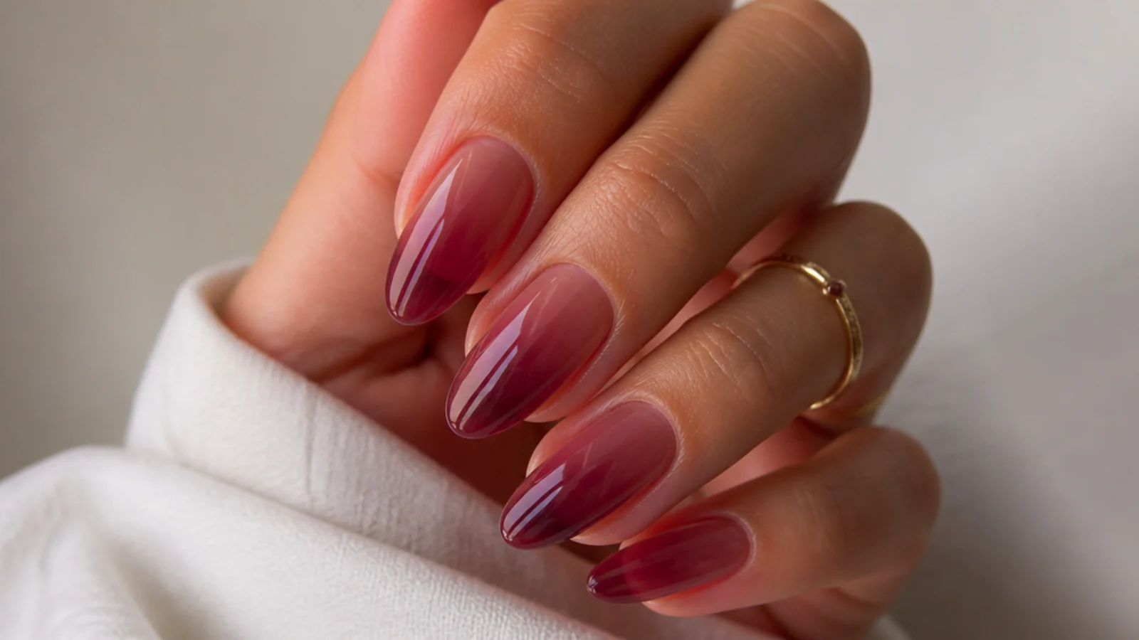 Almond nails with a sheer translucent wine wash showing the natural nail through