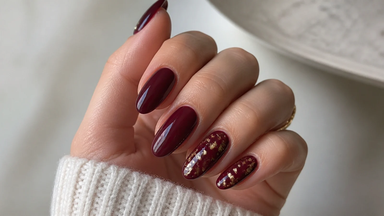 Almond nails in deep merlot with fine gold foil flecks on two accent nails