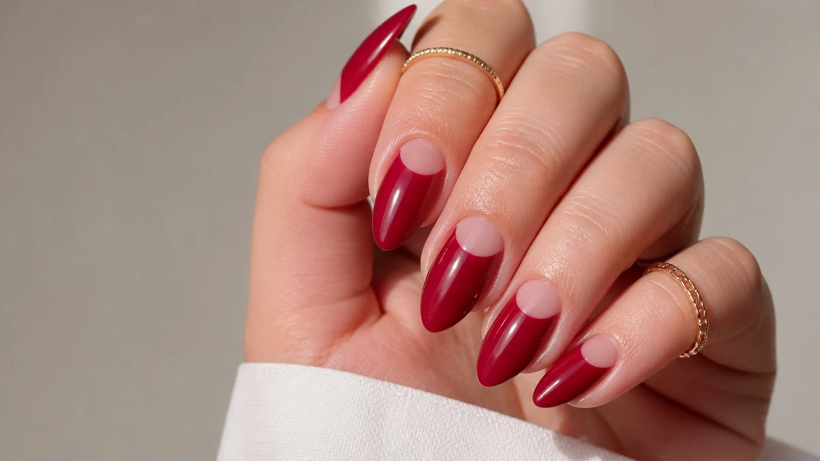 Almond nails with a sheer warm red painted around bare negative space at the base
