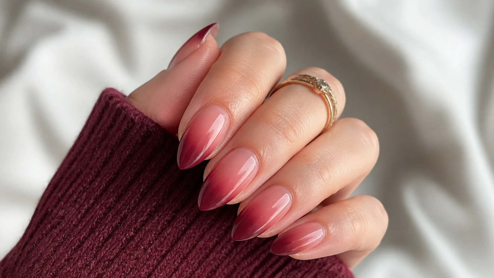 Almond nails with a soft ombre fading from nude at the base to deep berry at the tips
