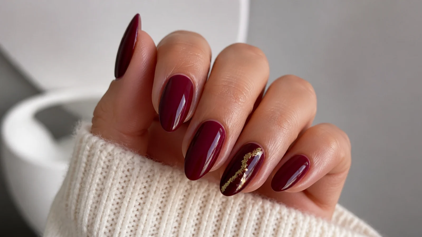 Oxblood nails with a fine gold foil line on one accent nail