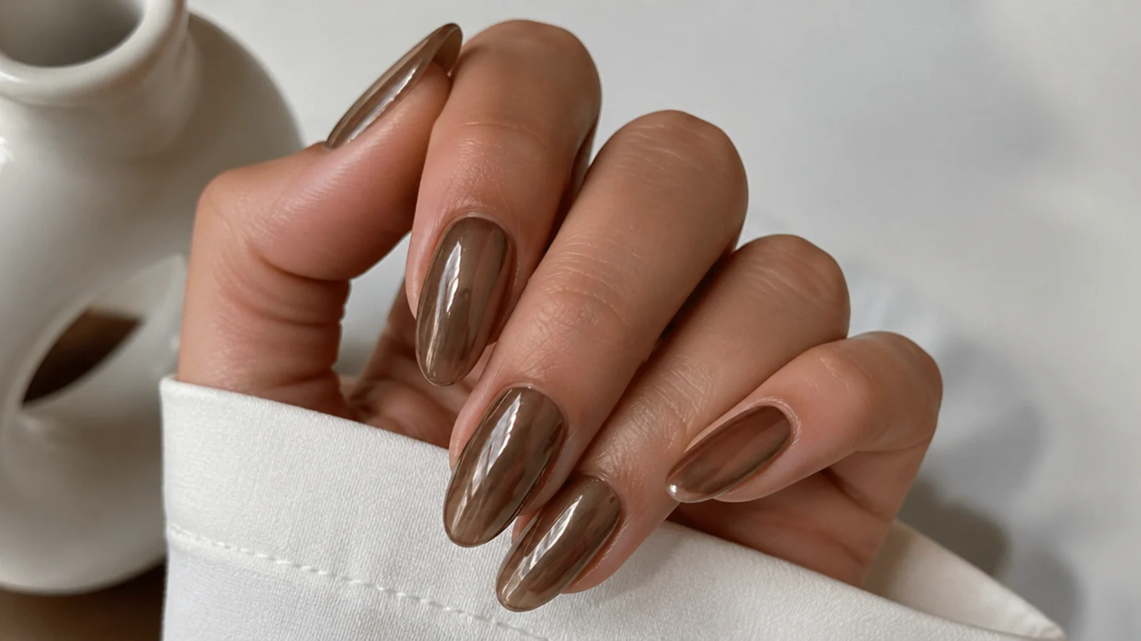 Warm mocha brown almond nails with a soft chrome sheen