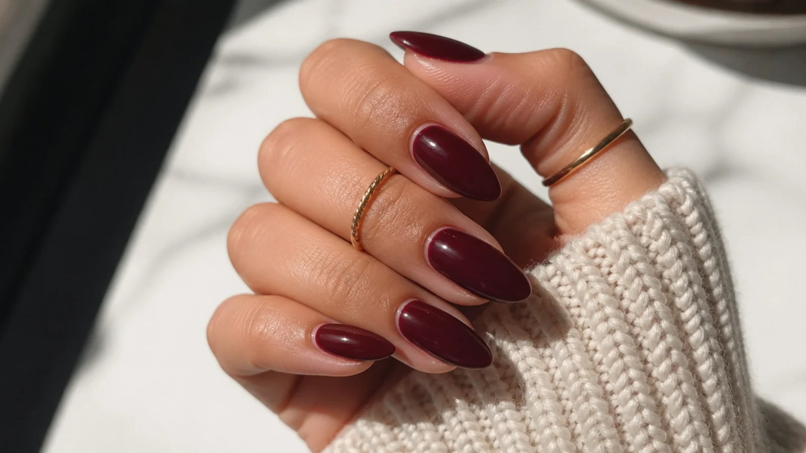 Sultry dark feminine almond nails in deep berry with a glossy finish