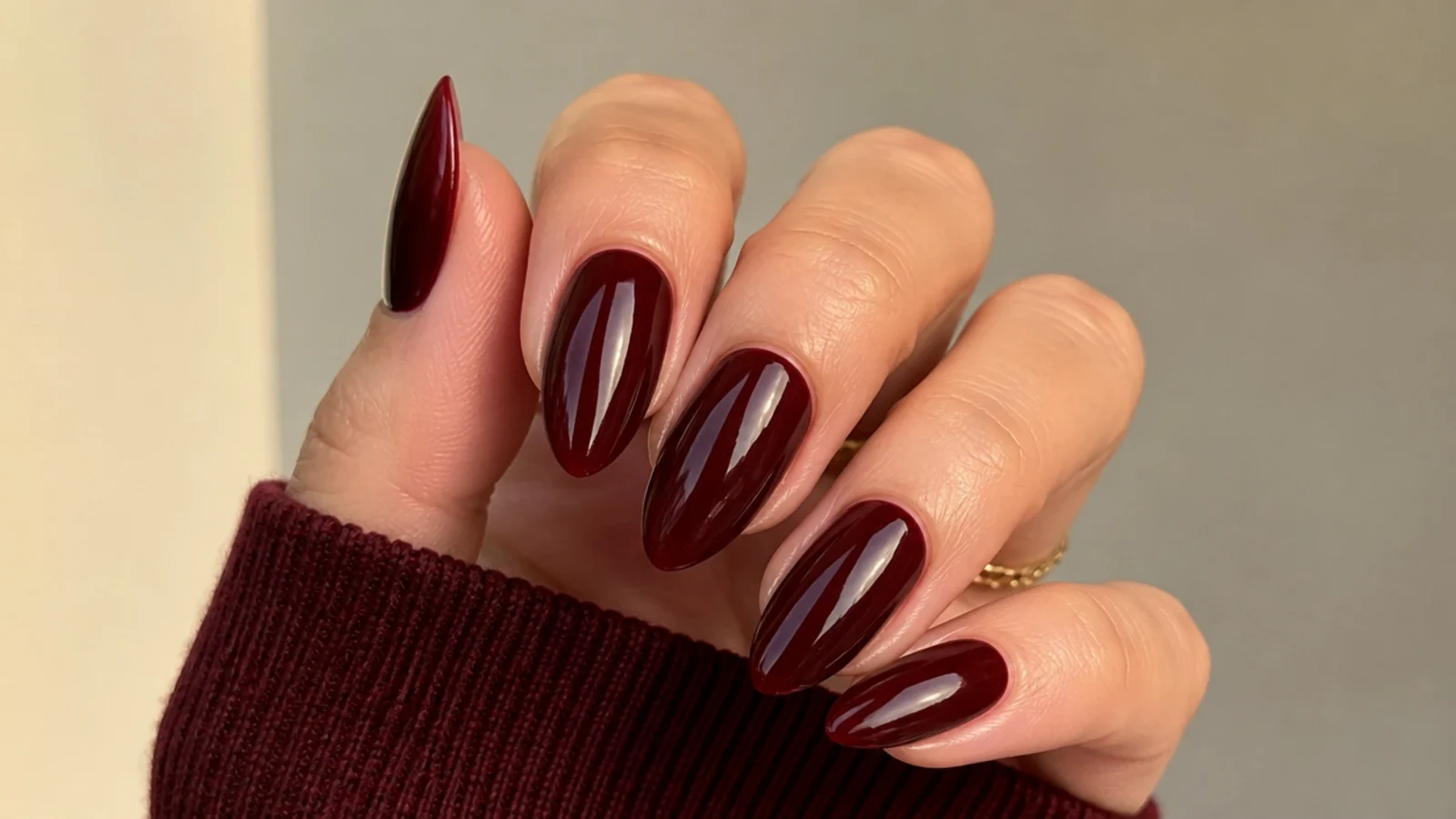 Glossy oxblood almond nails with a deep warm red-brown finish