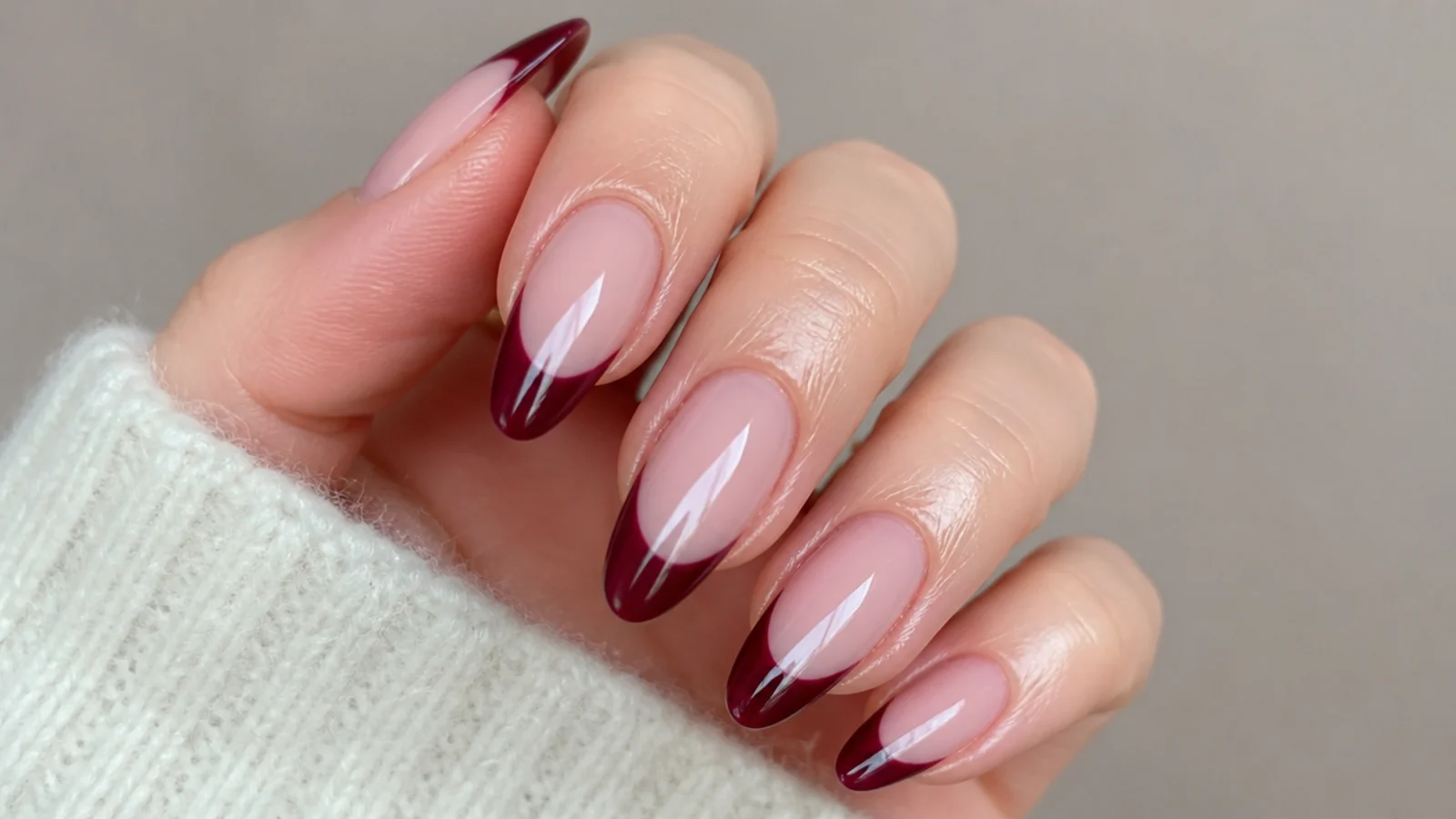 Almond nails with a sheer nude base and deep berry French tips