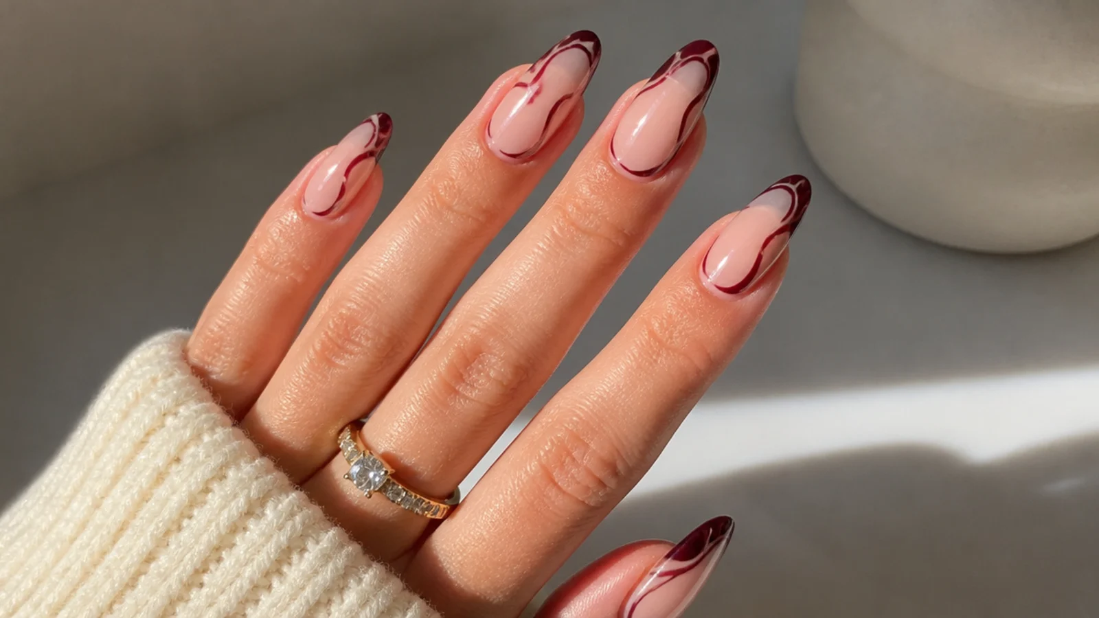 Sheer almond nails with a deep berry abstract swirl and bare negative space