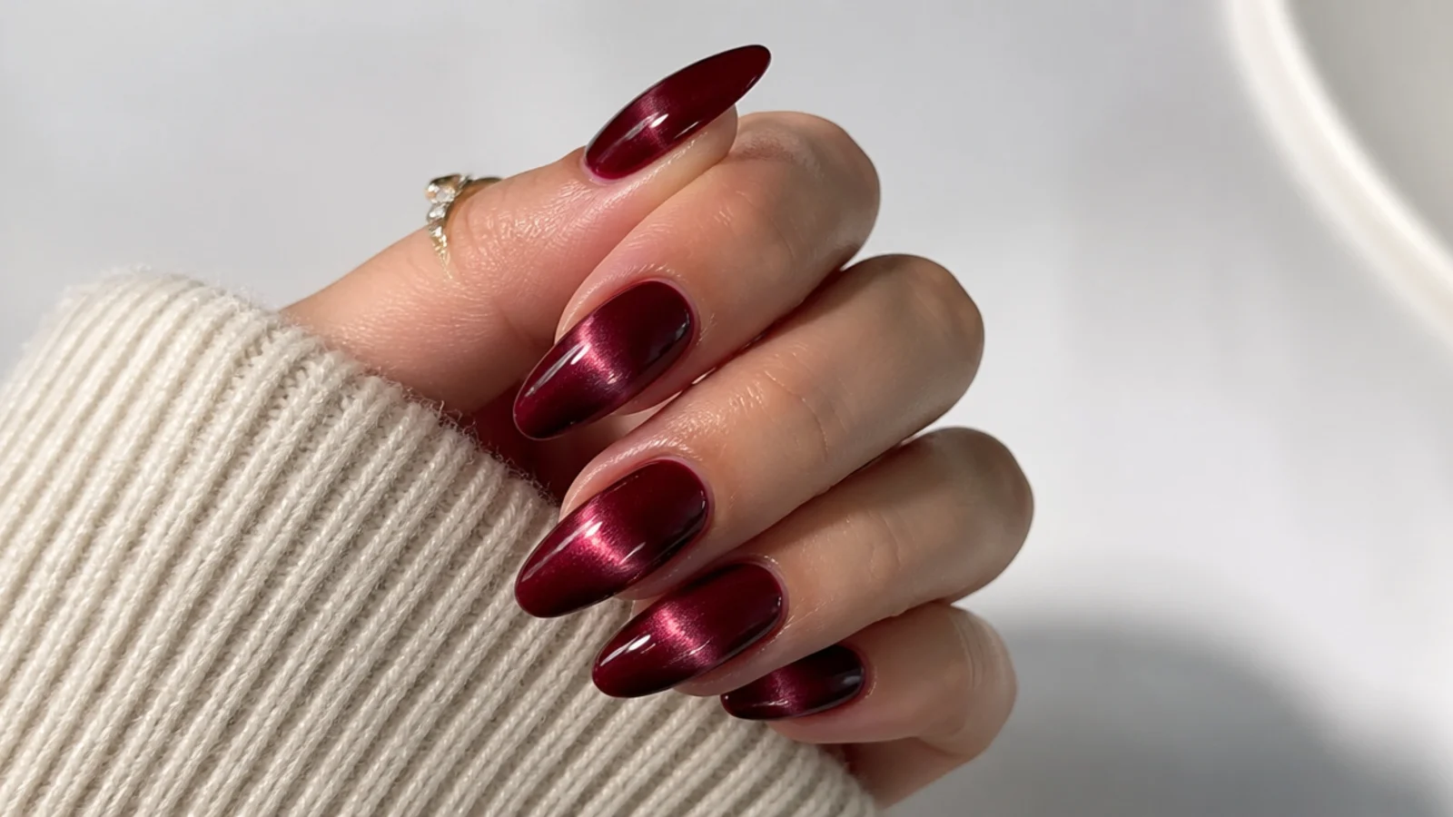 Deep merlot almond nails with a soft magnetic cat-eye light streak