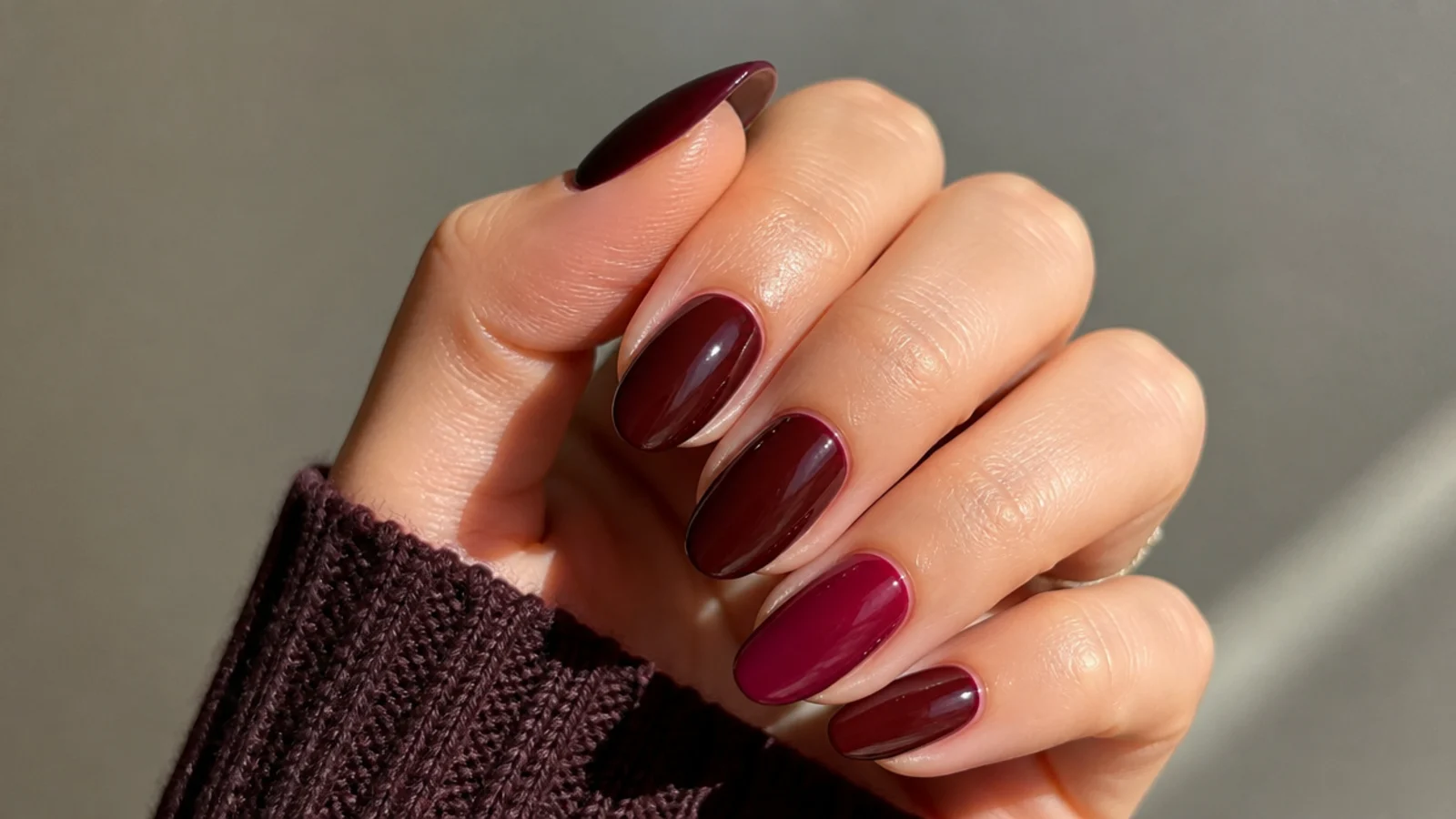 Glossy warm oxblood and berry nails showing the dark feminine warm-toned mood